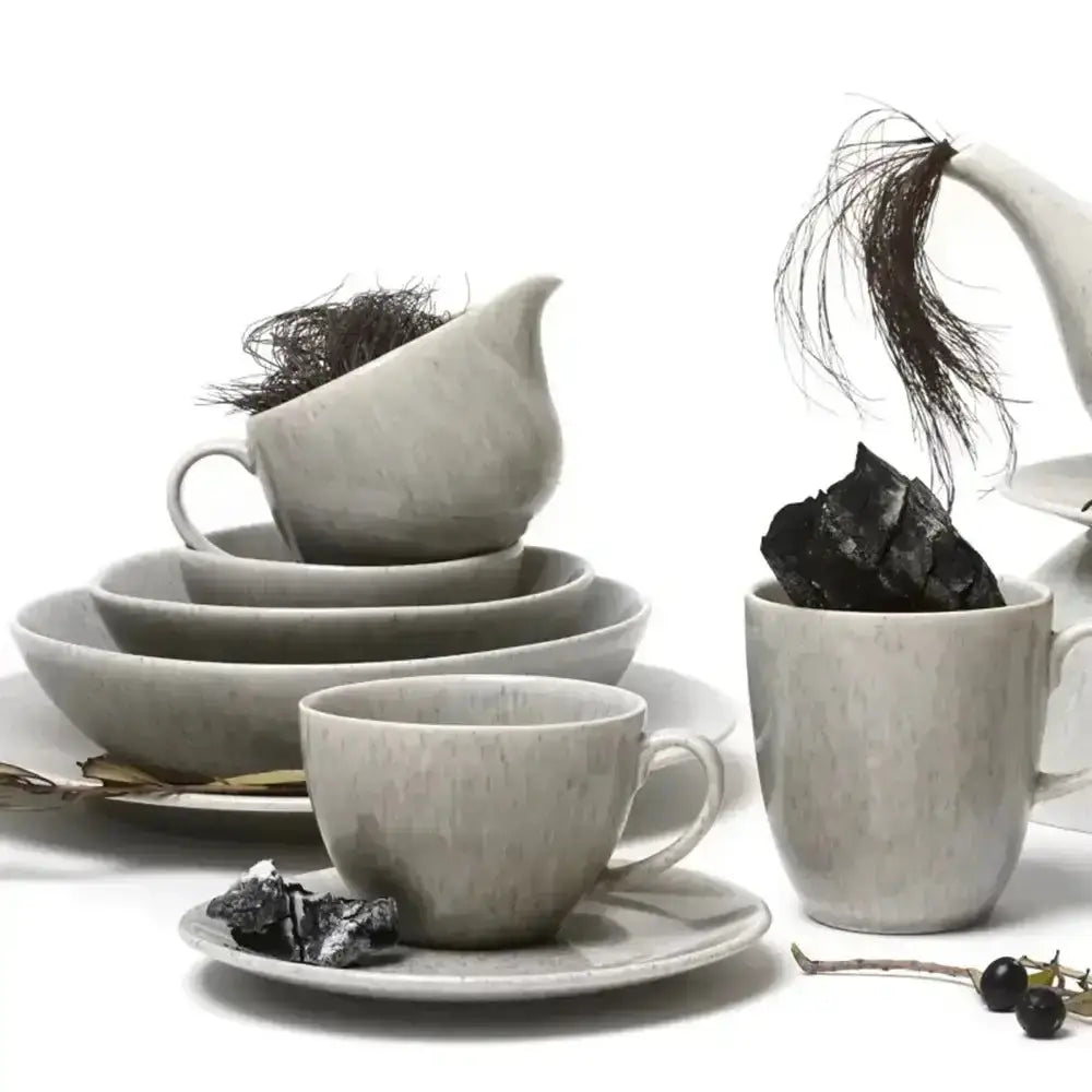 Set of gray ceramic tea cups, saucers, and teapot on a white background