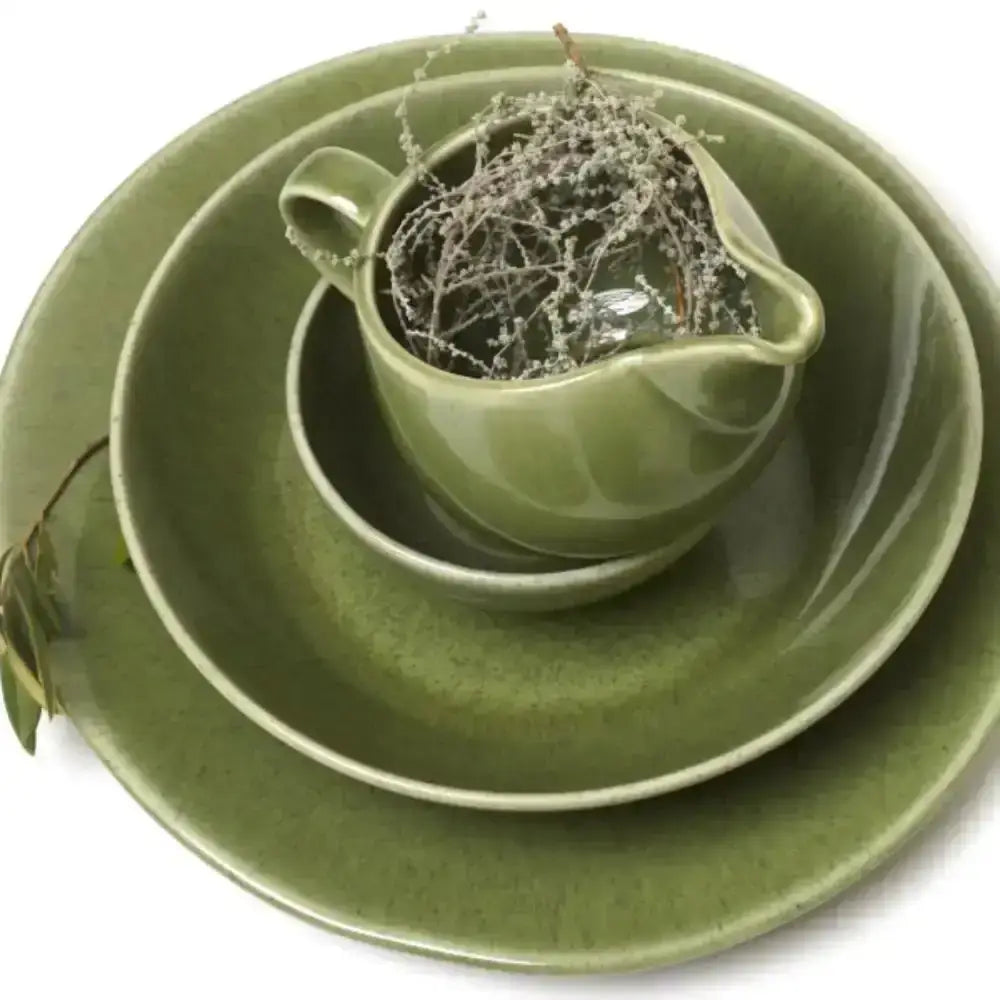 Green ceramic tableware set with a small pitcher on a white background