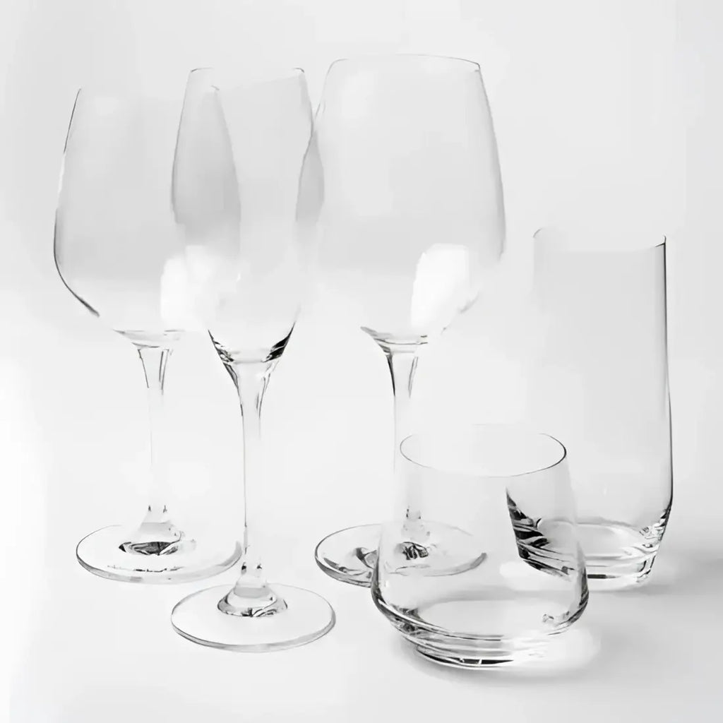 Set of clear glassware including wine glasses and a bowl on a white background
