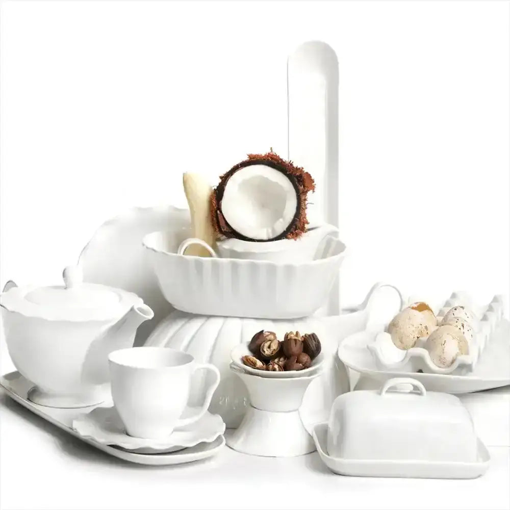 Collection of white ceramic dishes with food items on a white background