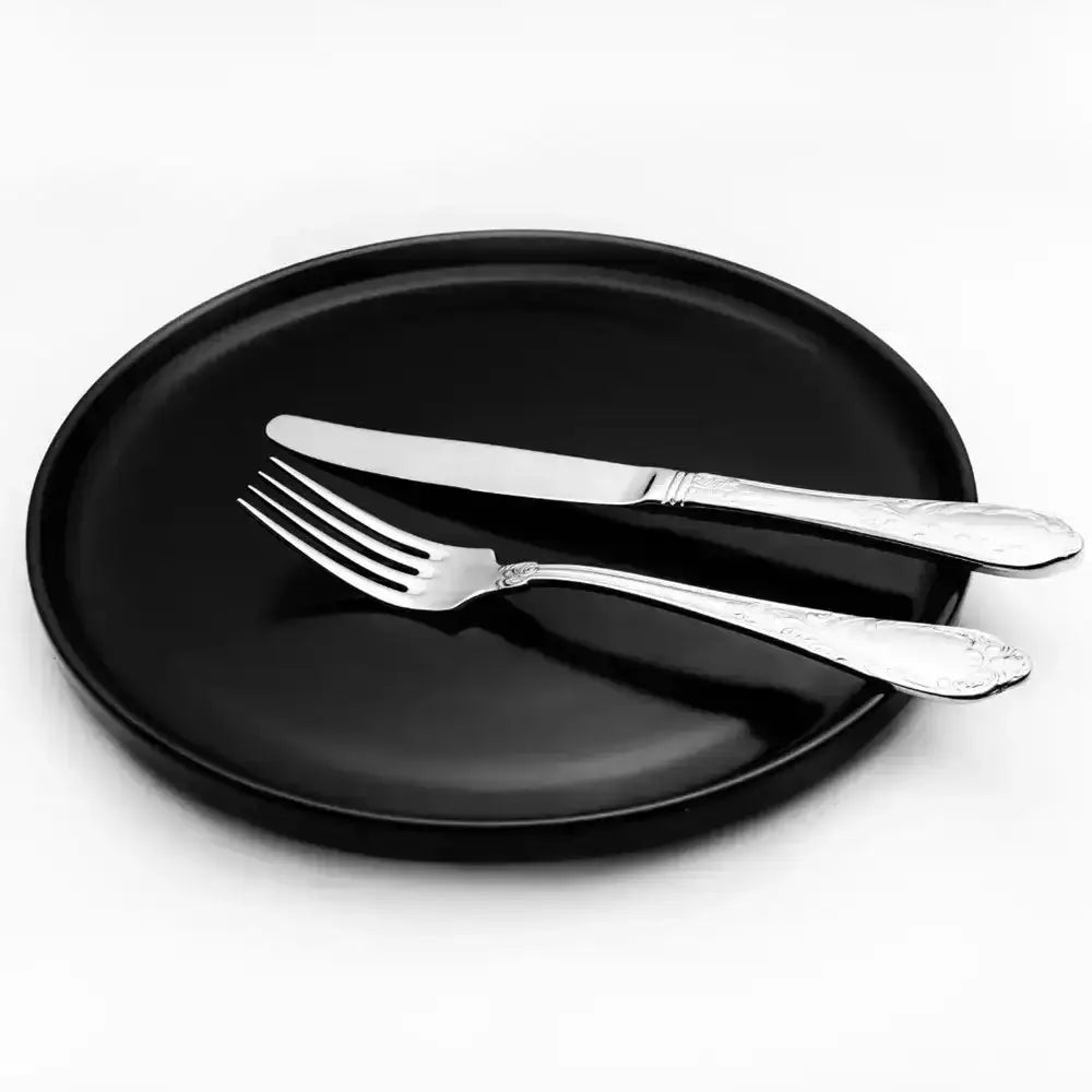 Black plate with silver knife and fork on a white background