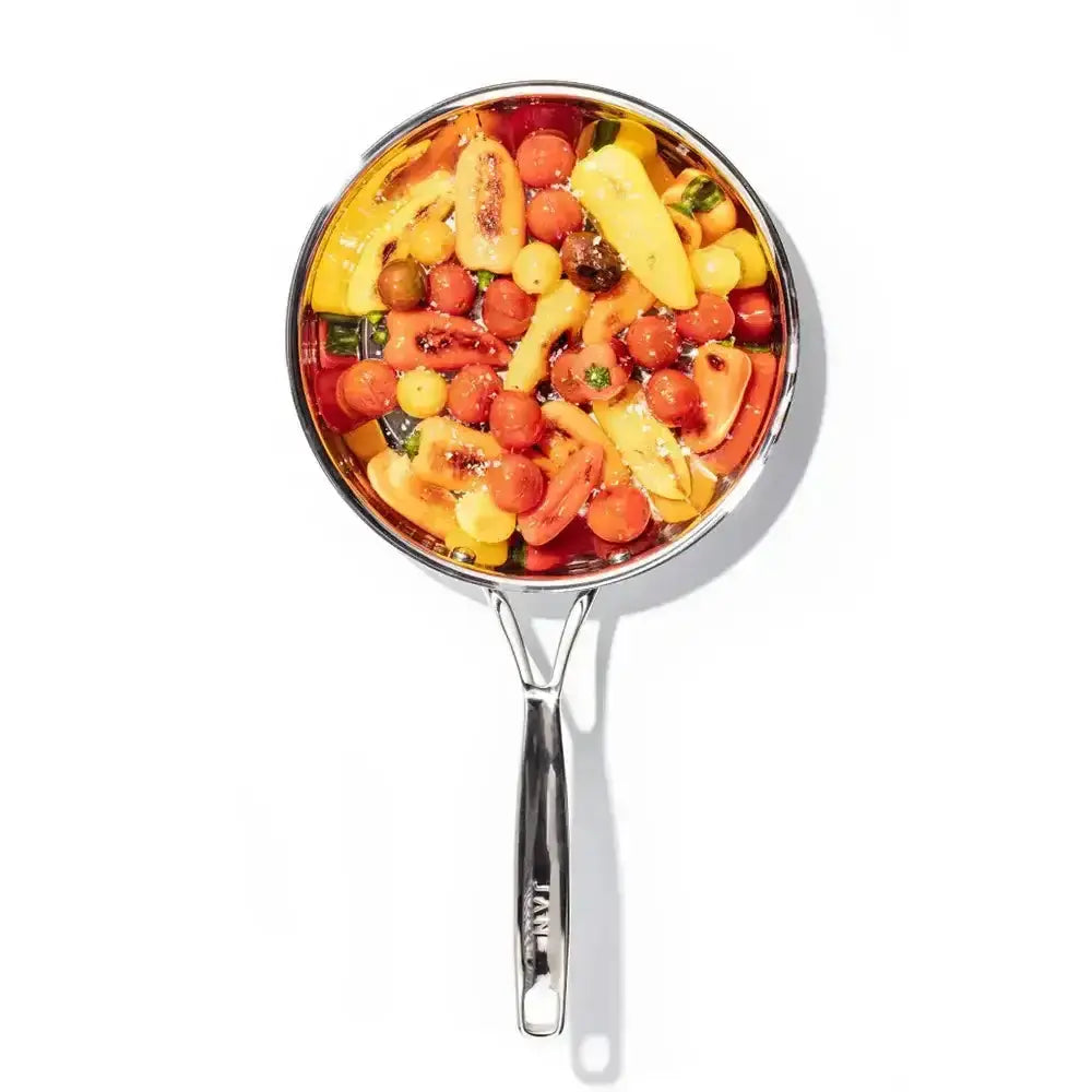 Stainless steel frying pan with colorful vegetables on a white background
