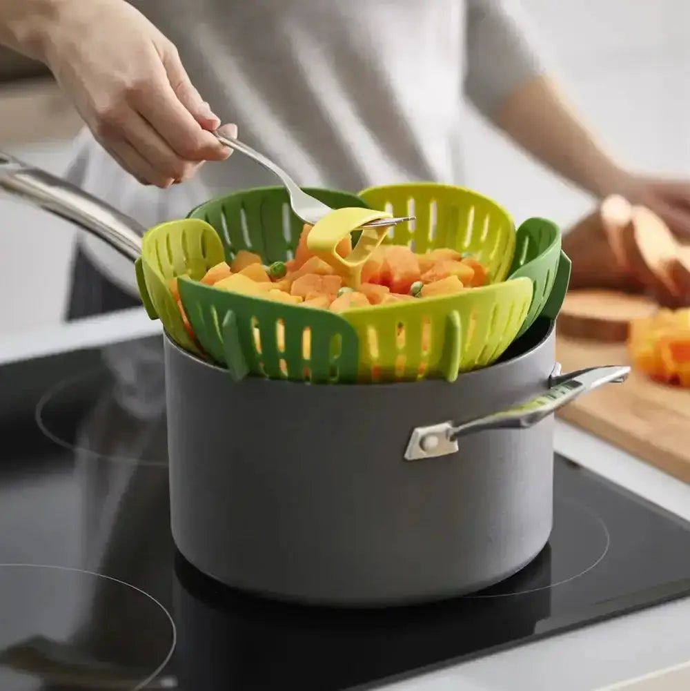 Person using a green kitchen tool to transfer food from a pot on a stove.