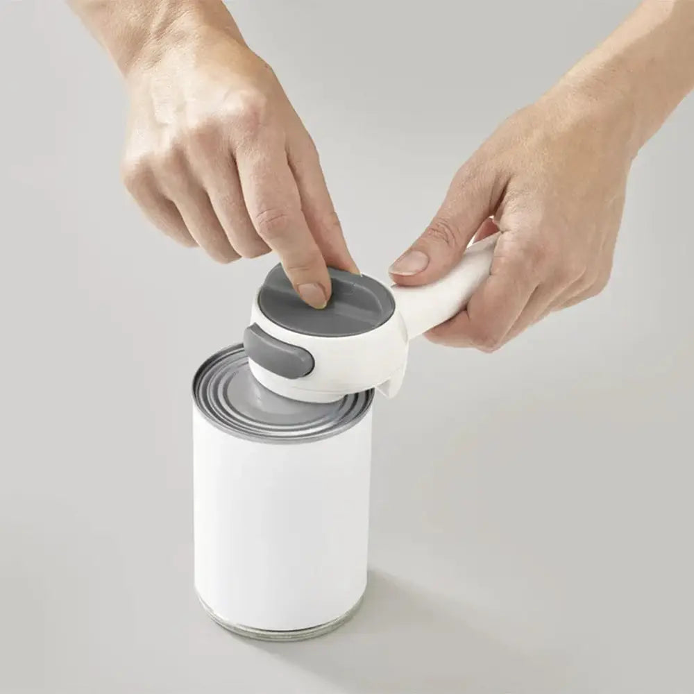 Person using a can opener on a white can against a light gray background