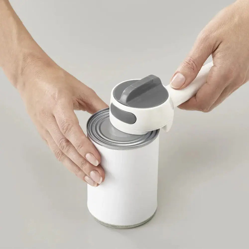 Person using a can opener on a can with a white background
