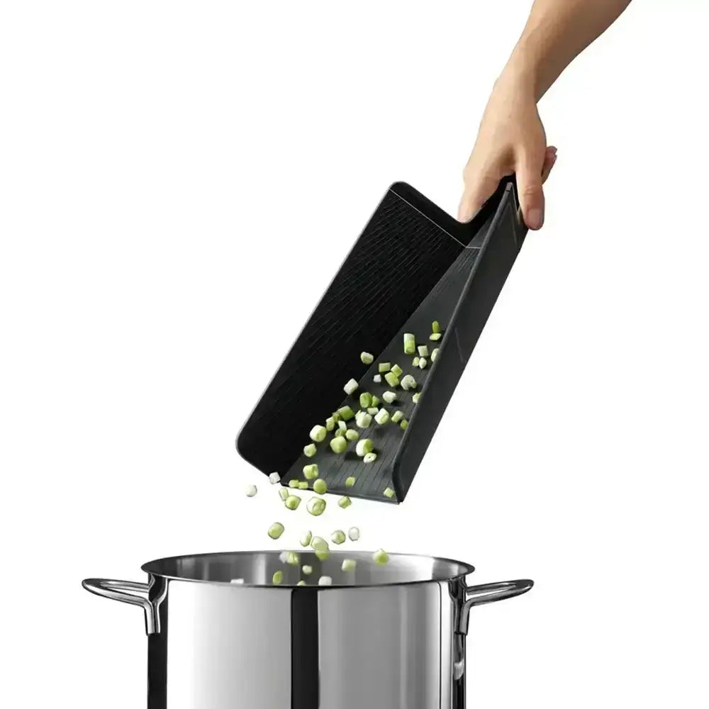 Black slotted spoon transferring green vegetables into a pot on a white background