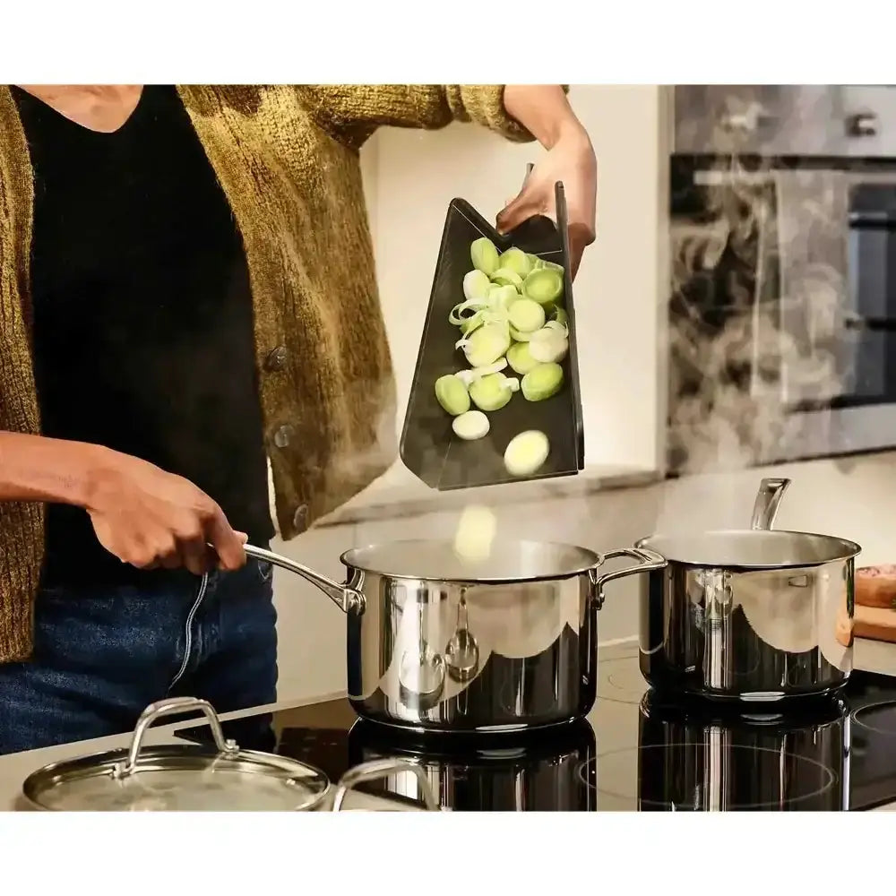 Person cooking in a kitchen with stainless steel pots and green vegetables.