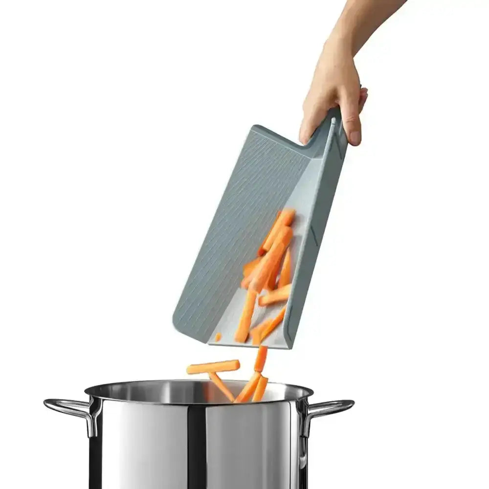 Person using a gray cutting board to transfer carrots into a pot on a white background