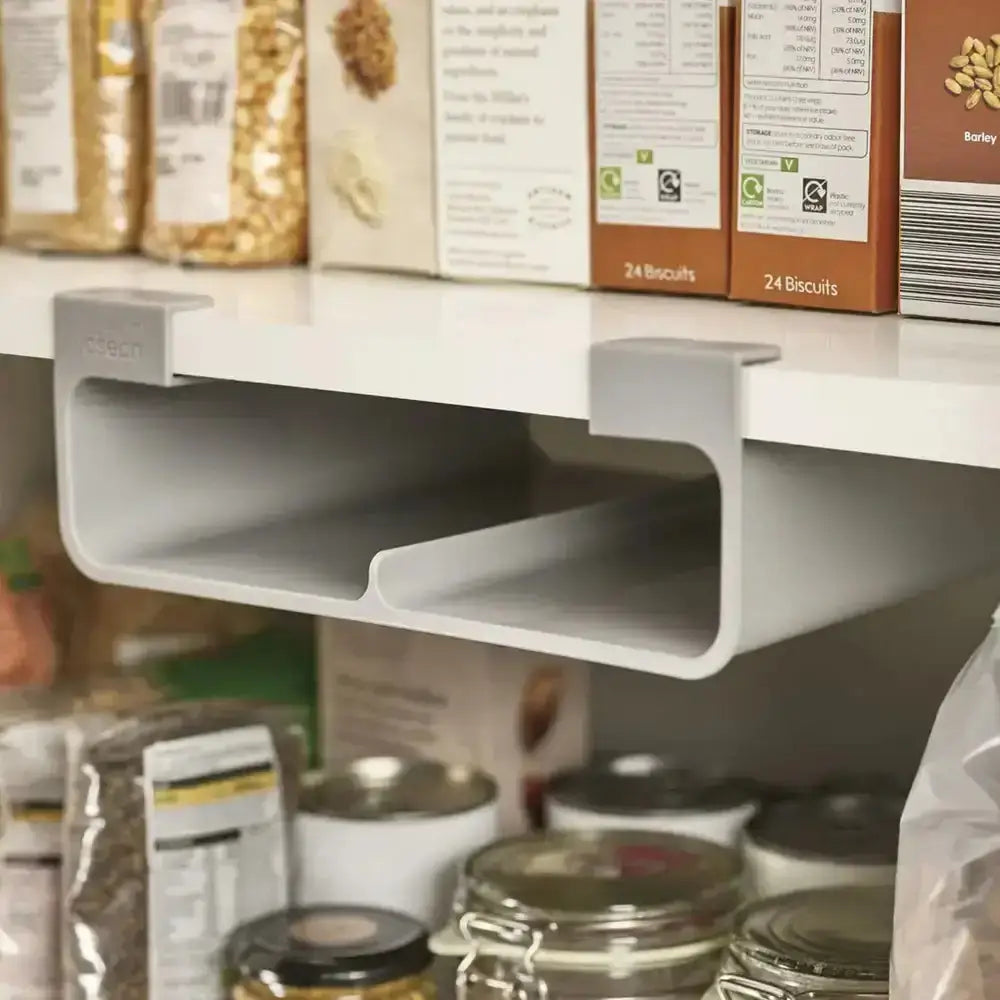 Kitchen shelf with a gray under-shelf storage organizer holding boxes and jars.