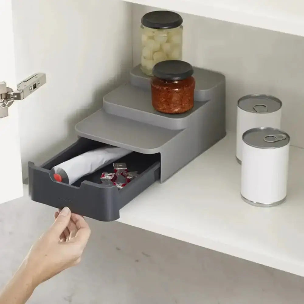 Gray kitchen storage organizer with a drawer being pulled out, containing items like jars and cans.