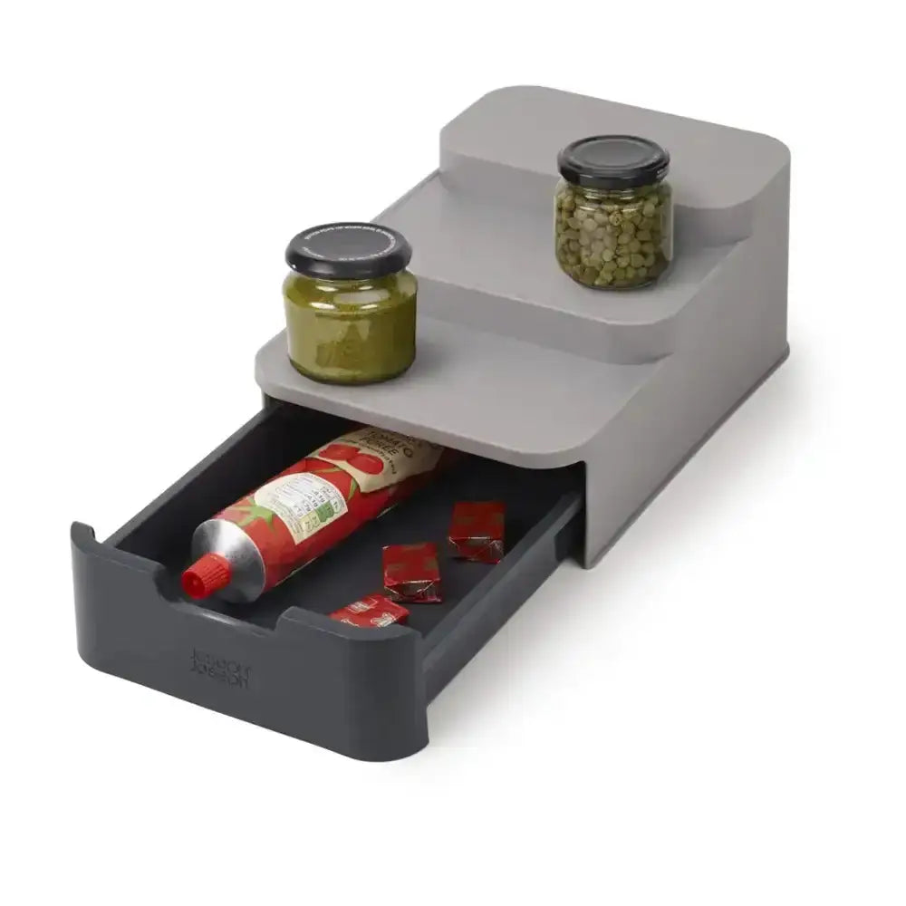 Gray kitchen organizer with jars and a tube on a white background