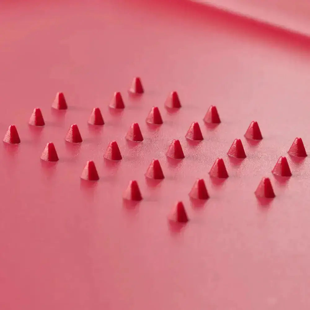 Red joseph joseph cut and carve plus chopping board with plastic cone spikes on a matching red surface