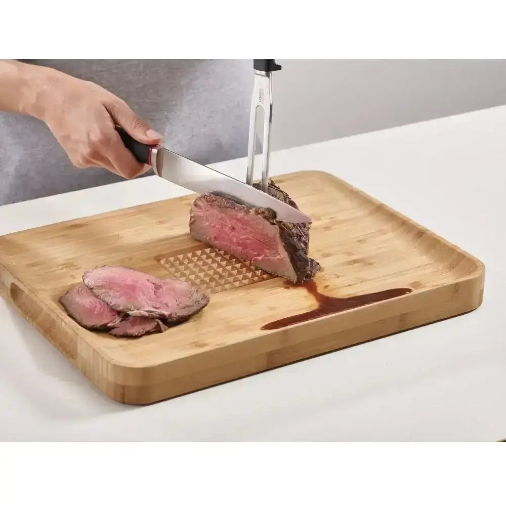 Person slicing beef on a wooden cutting board with a knife