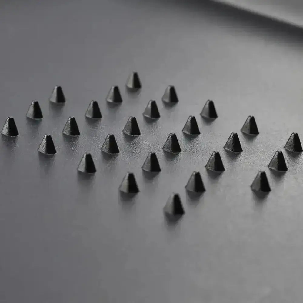 Black pyramid-shaped objects arranged in a pattern on a gray surface