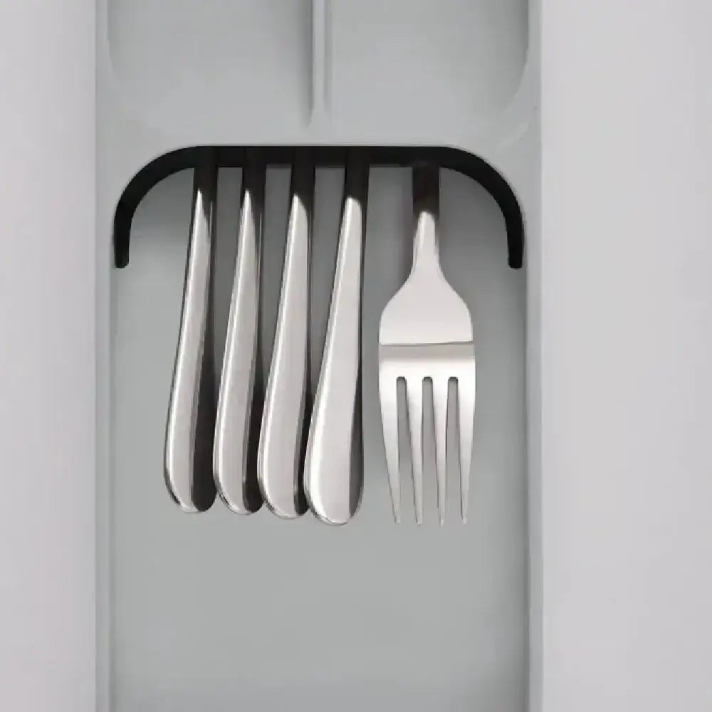 Set of silver cutlery including a fork and knives in a black holder on a light gray background