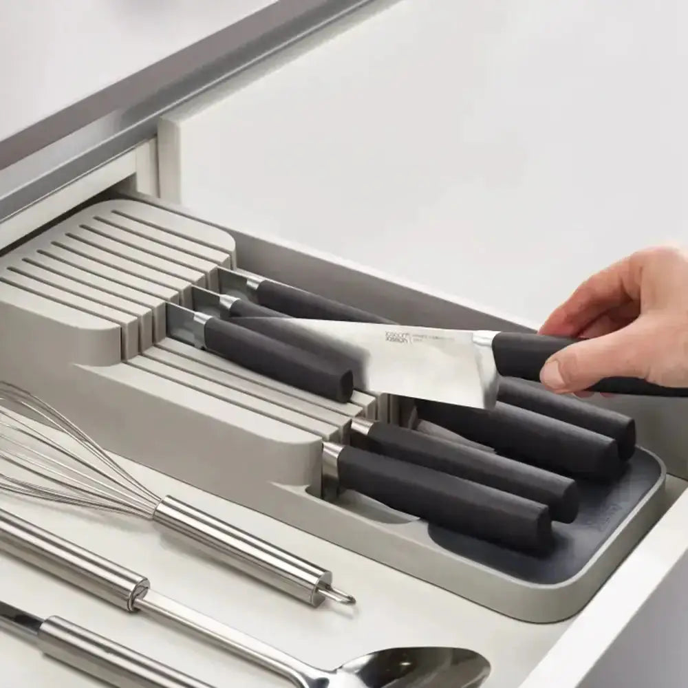 Knife set with black handles in a gray knife block on a white kitchen counter.