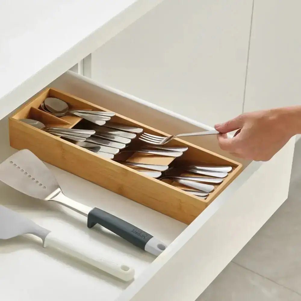 Wooden cutlery organizer being used to store silverware in a kitchen drawer.