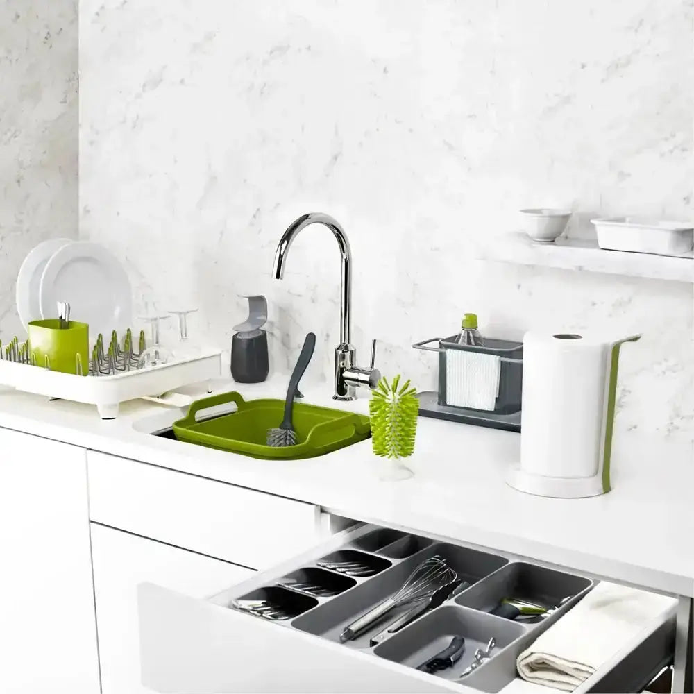 Modern kitchen with white countertops, a sink, and various utensils including green cutting boards and a knife.