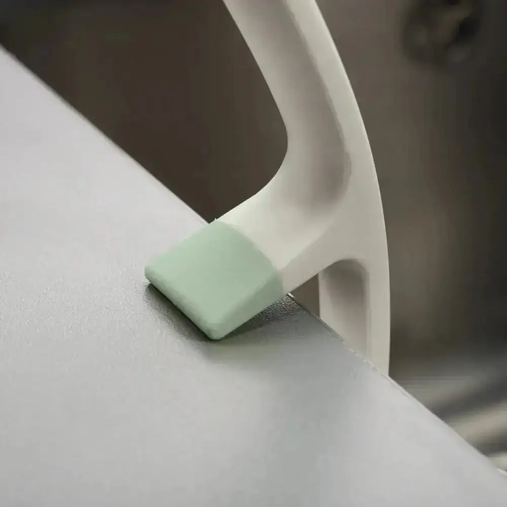 Light green dish brush resting on a sink with a blurred background