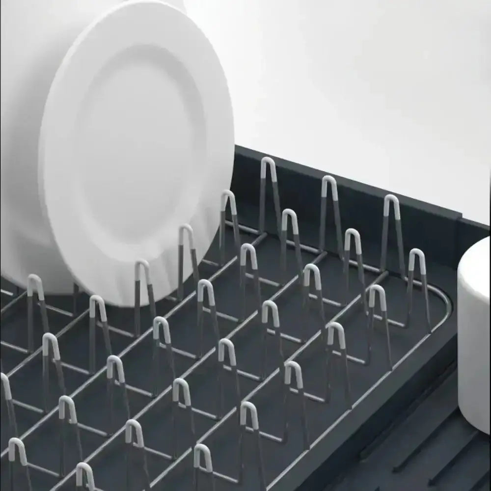 Dish rack with white plates and cups on a light gray background