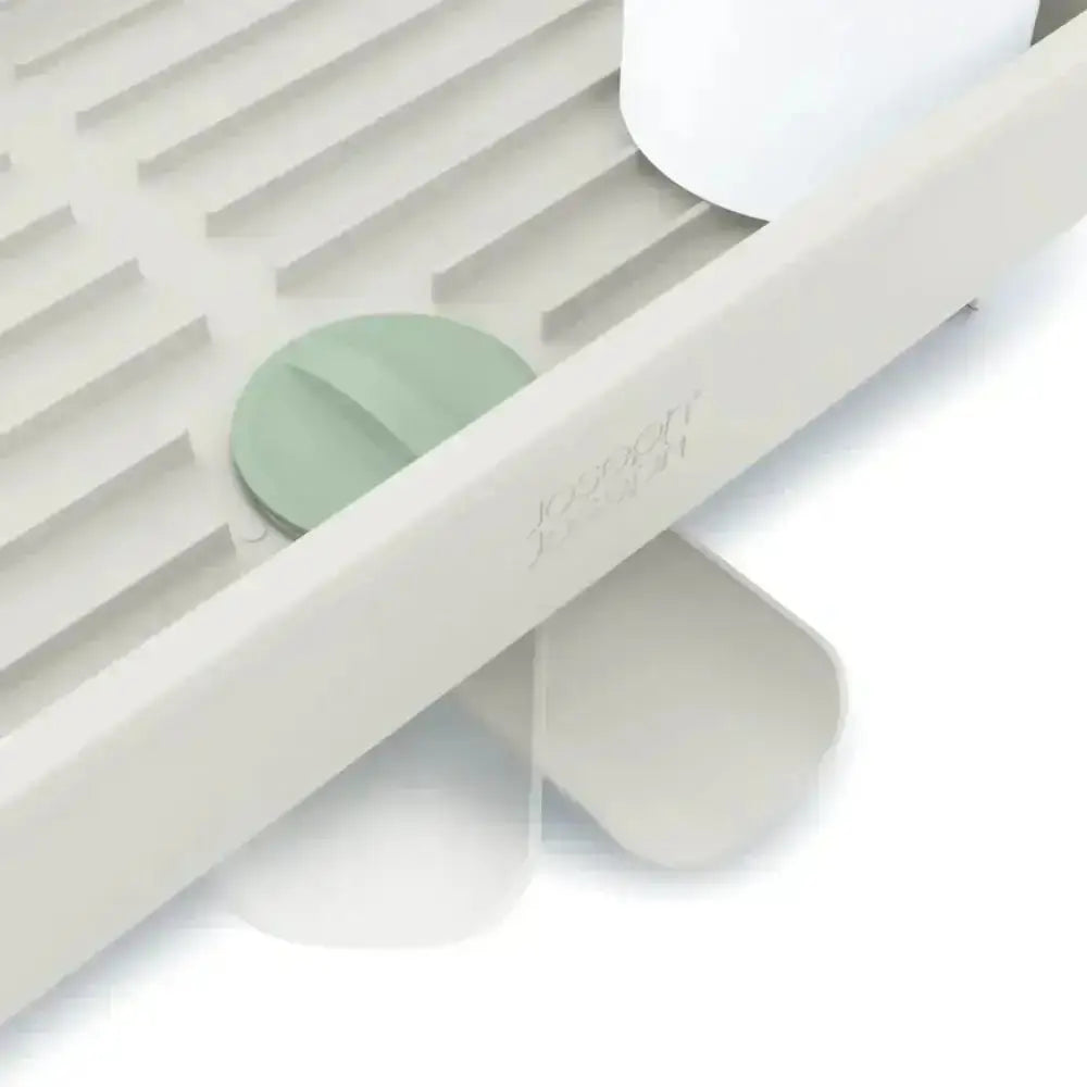 White kitchen tool with a green component on a light gray background