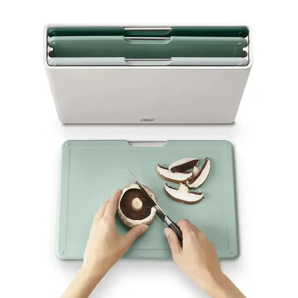 Person cutting mushrooms on a green cutting board with a knife, next to a white container.