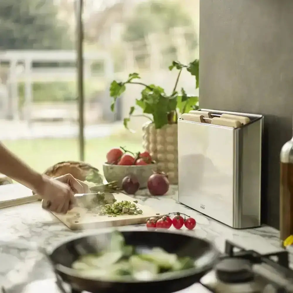 Person preparing food on a kitchen counter with a knife block and window in the background