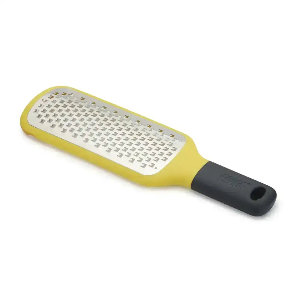 Yellow paddle grater with black handle on a white background