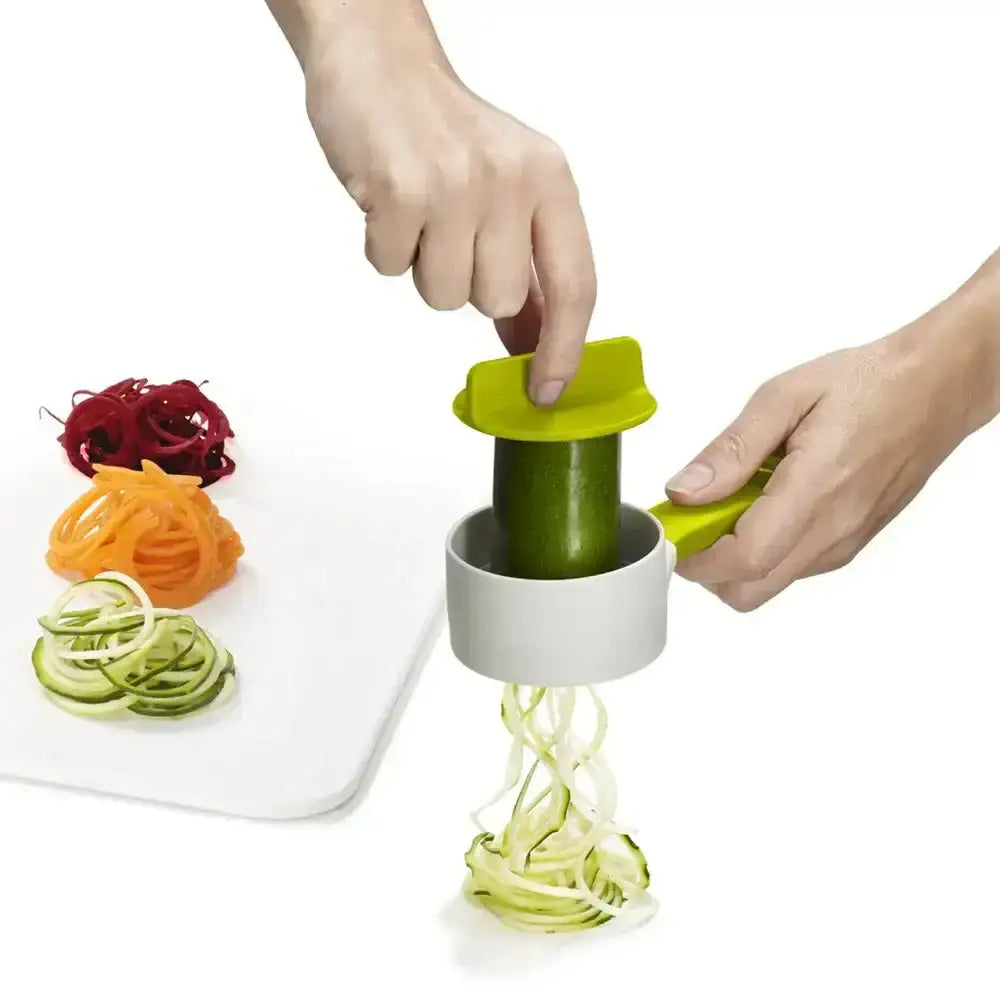 Person using a spiralizer to create zucchini noodles on a white background