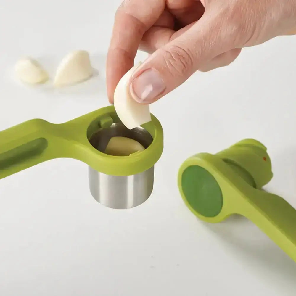 Green garlic press being used to crush garlic cloves on a white background