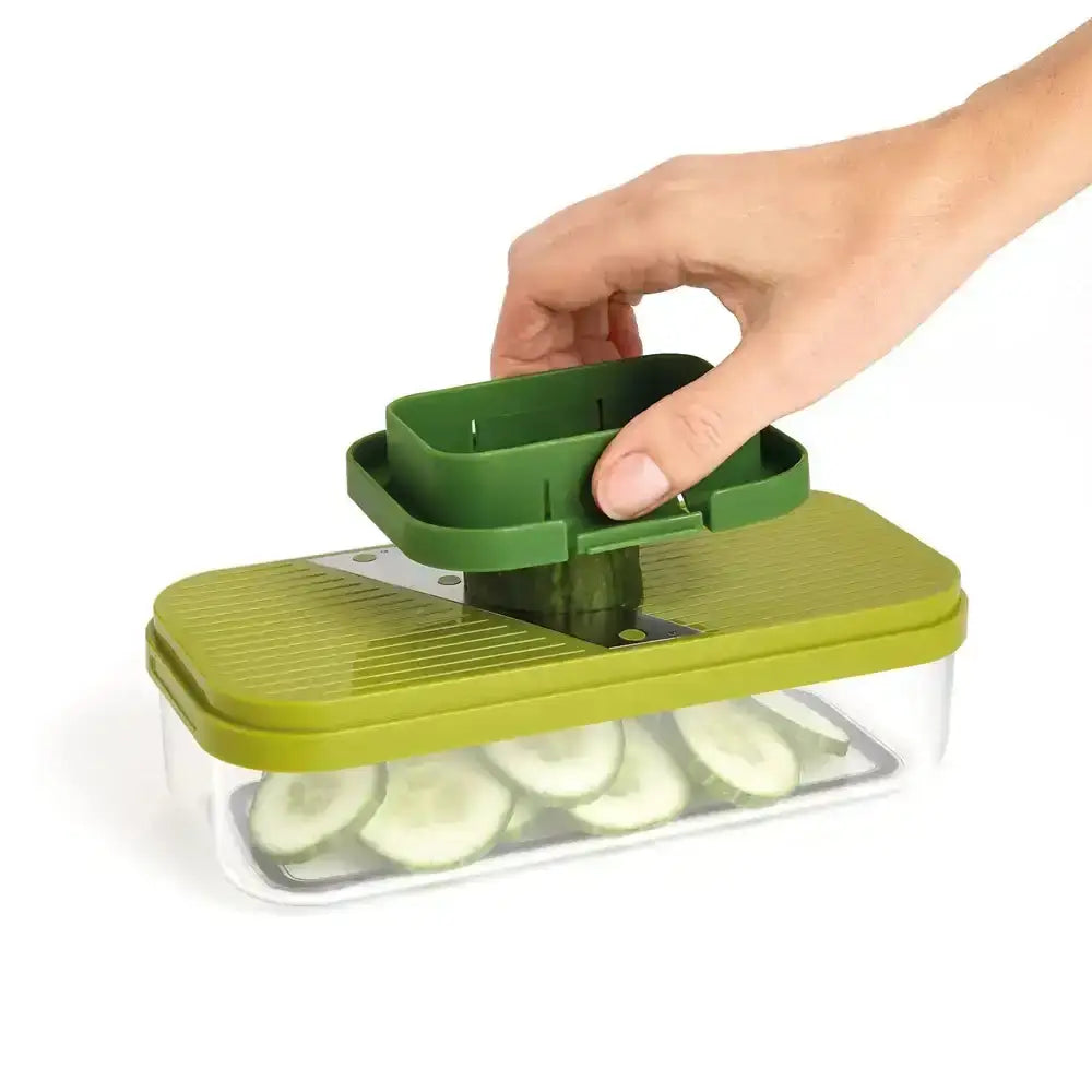 Green vegetable slicer with cucumbers being sliced on a white background