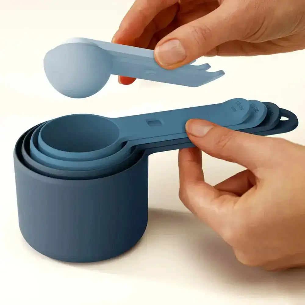Set of blue measuring cups and spoons held by hands on a light background