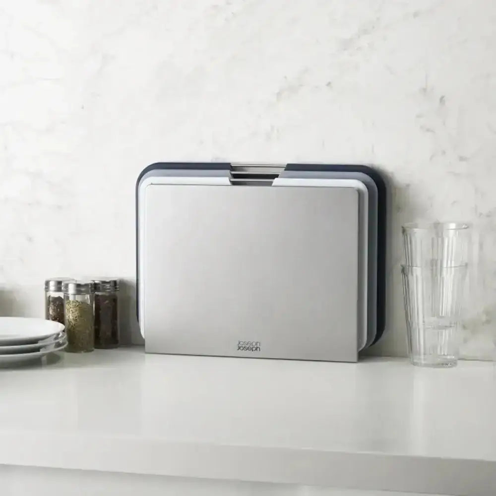 Stackable cutting boards on a kitchen counter with a white tiled wall background