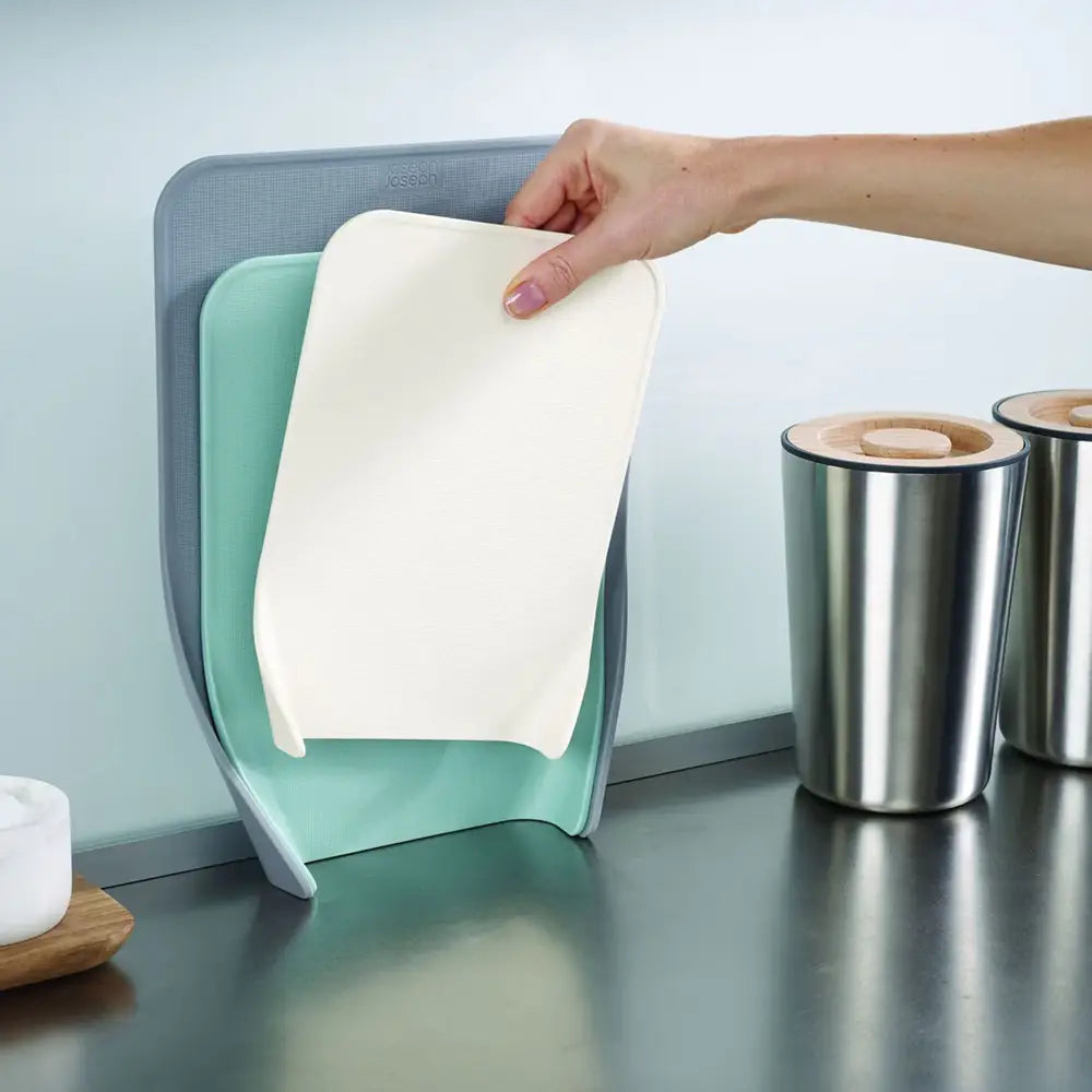 Person holding a white paper towel over a teal paper towel holder on a kitchen counter.