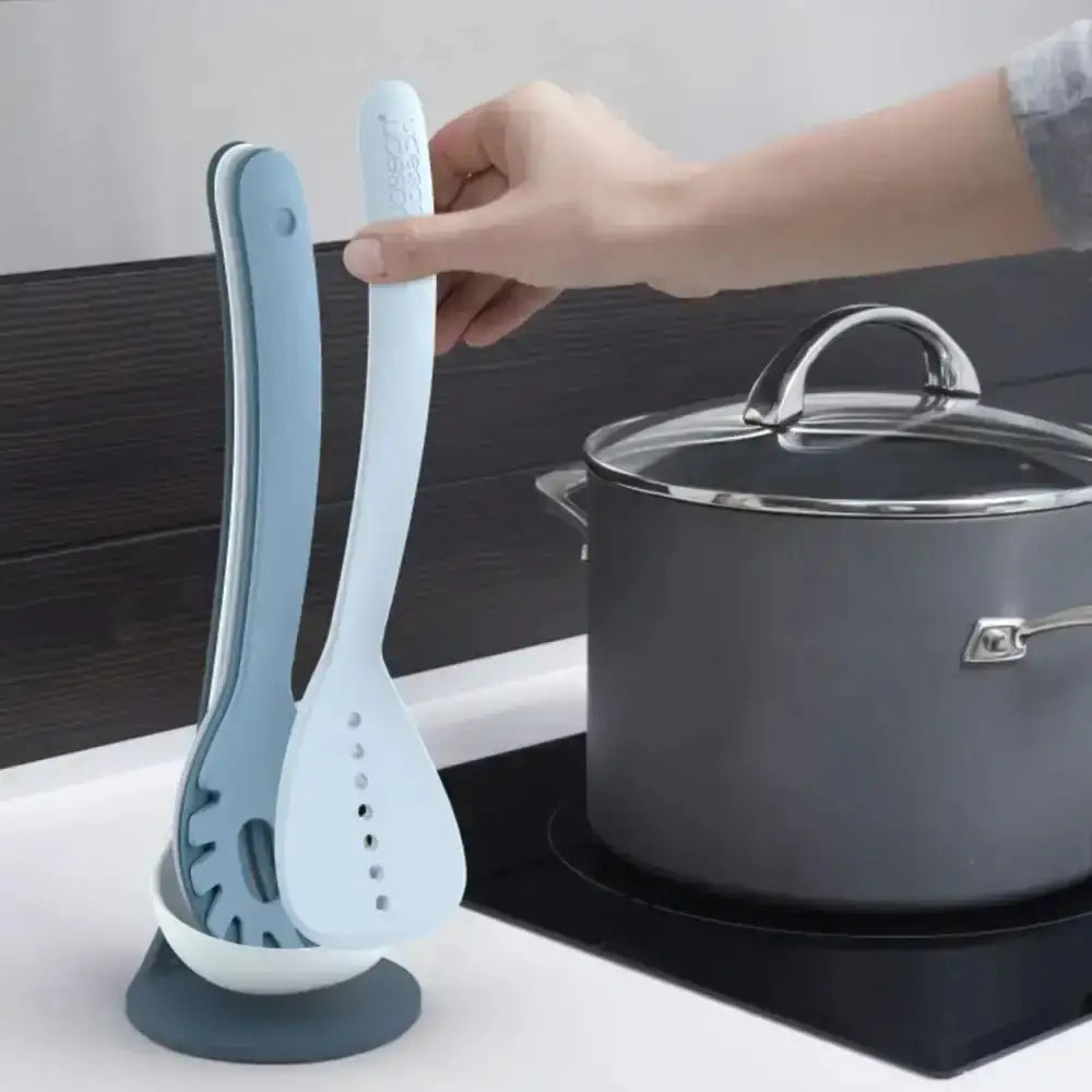 Two kitchen utensils held by a hand with a pot in the background
