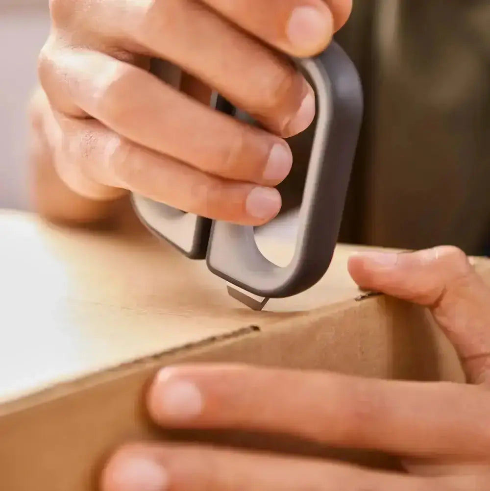Person using a box cutter on a piece of cardboard 