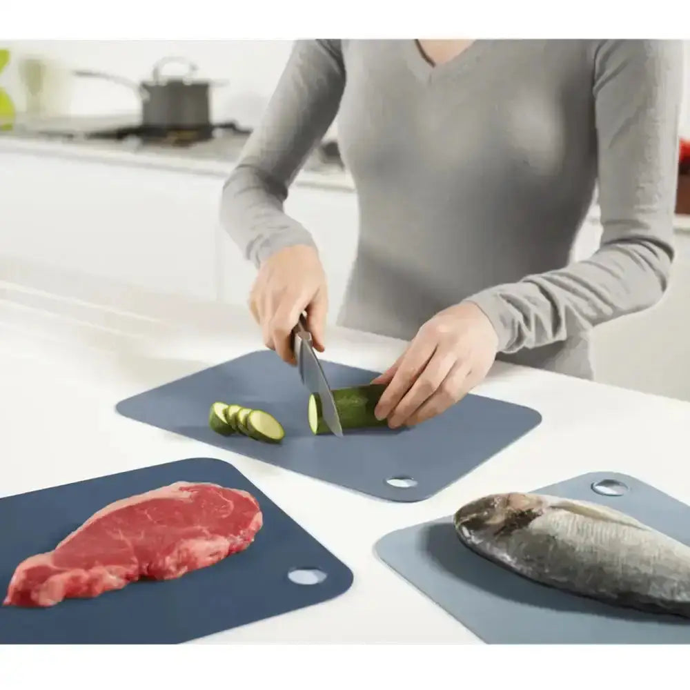 Person using cutting boards with different food items on a kitchen counter