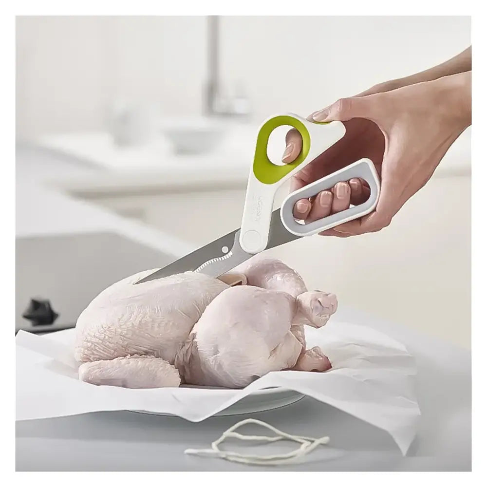 Shears being used to cut a chicken on a white surface