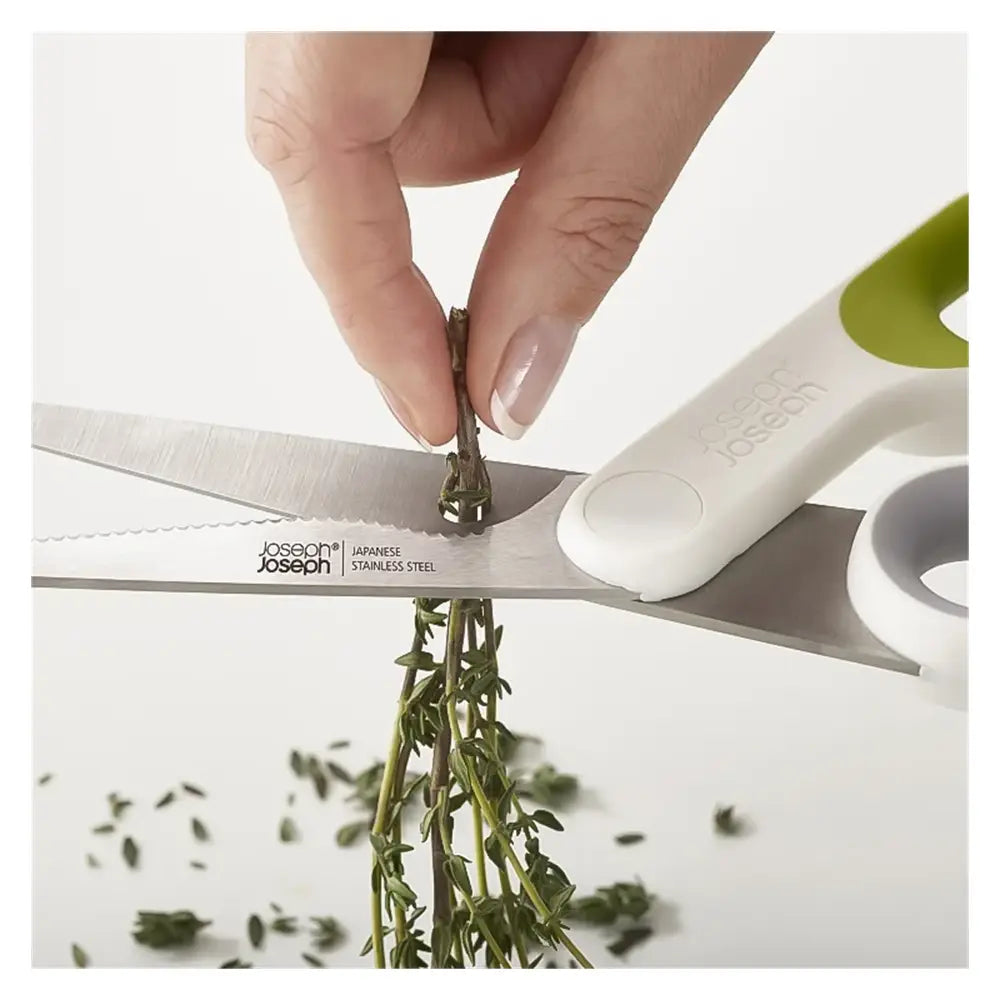 Hand using a pair of kitchen shears to trim thyme, with 'Joseph Joseph' branding visible.