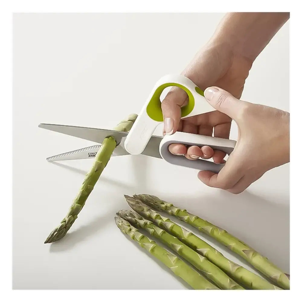 Person using a pair of asparagus shears to cut green asparagus on a white surface