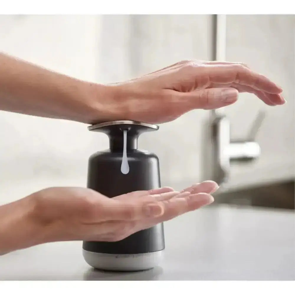 Black soap dispenser being used to dispense soap onto hands