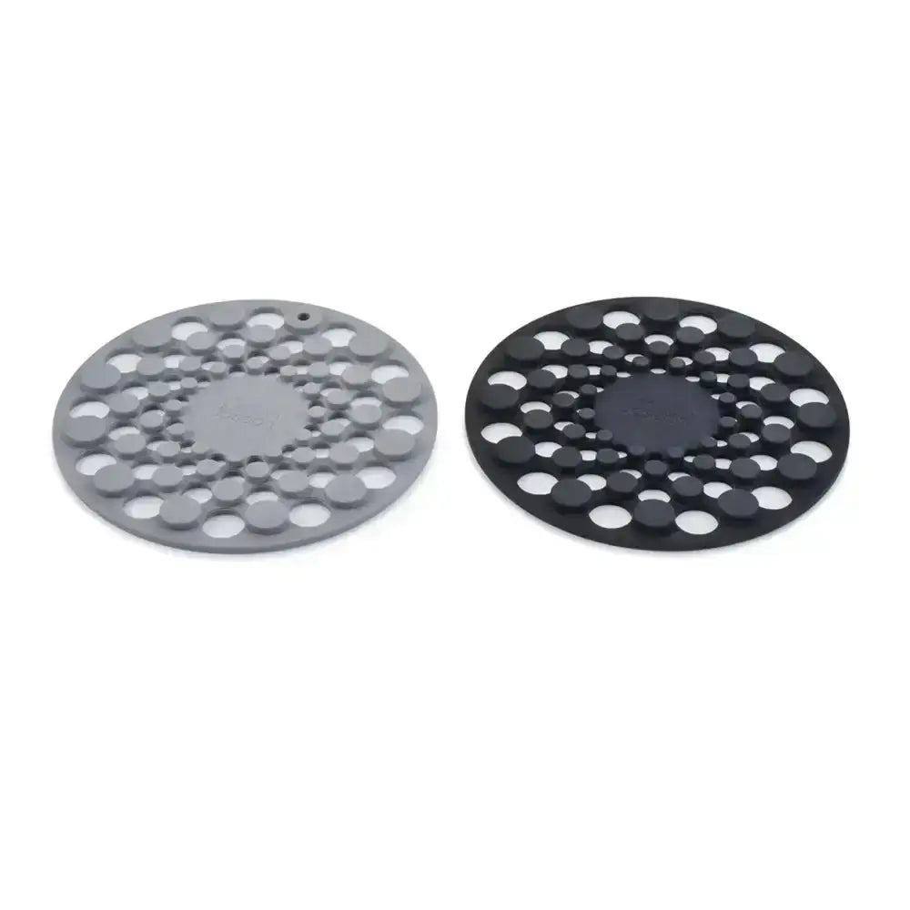 Two round silicone trivets, one gray and one black, on a white background.