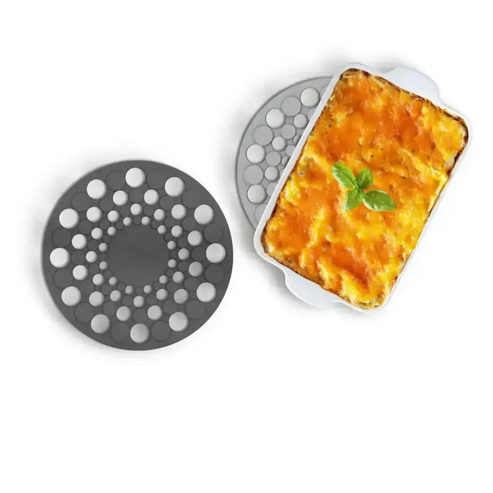 Silicone trivet with a dish of lasagna on a white background