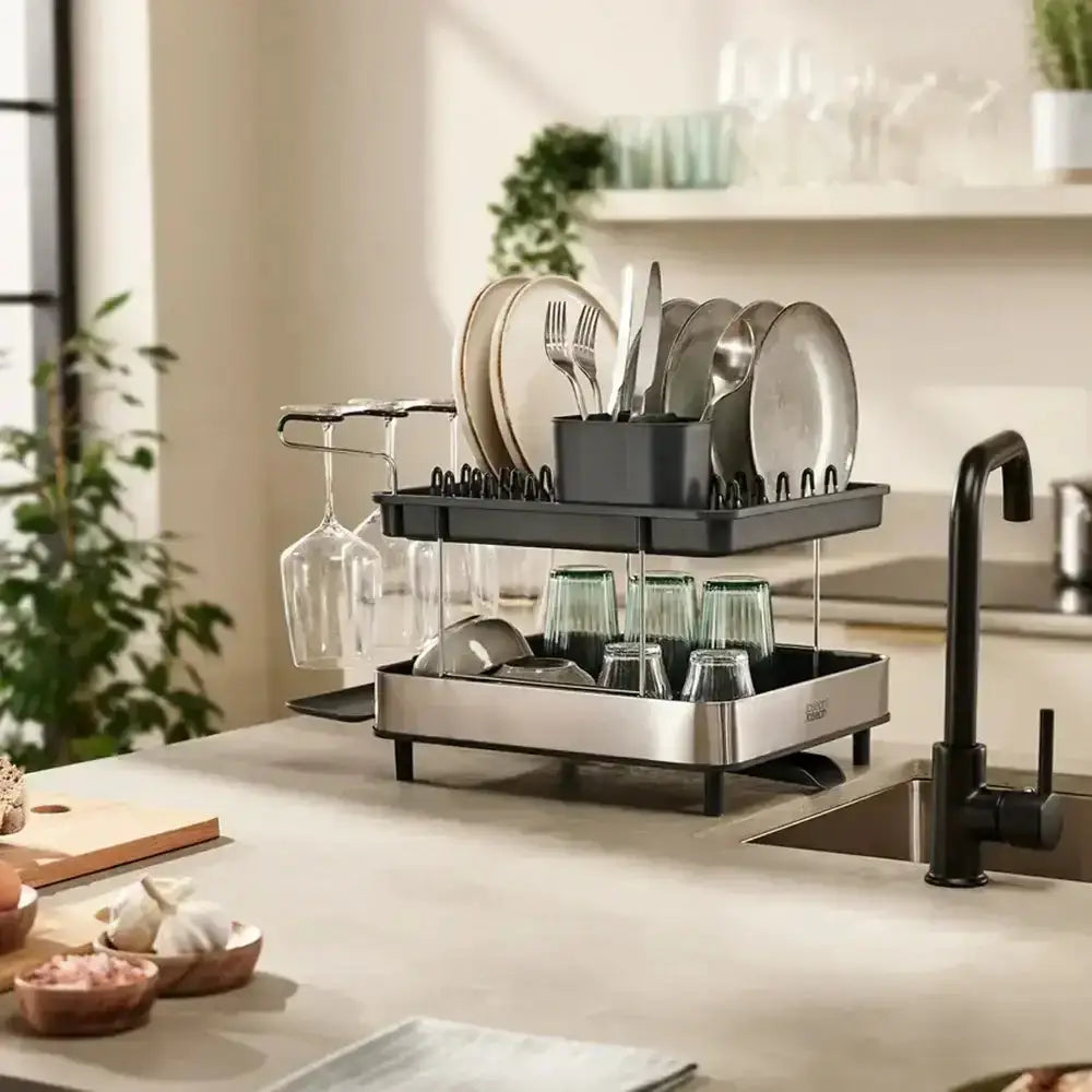 Kitchen dish rack with cutlery and glasses on a kitchen counter.