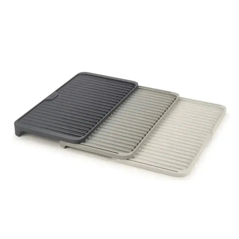 Three dish draining mats, one black, one gray and one white, on a white background