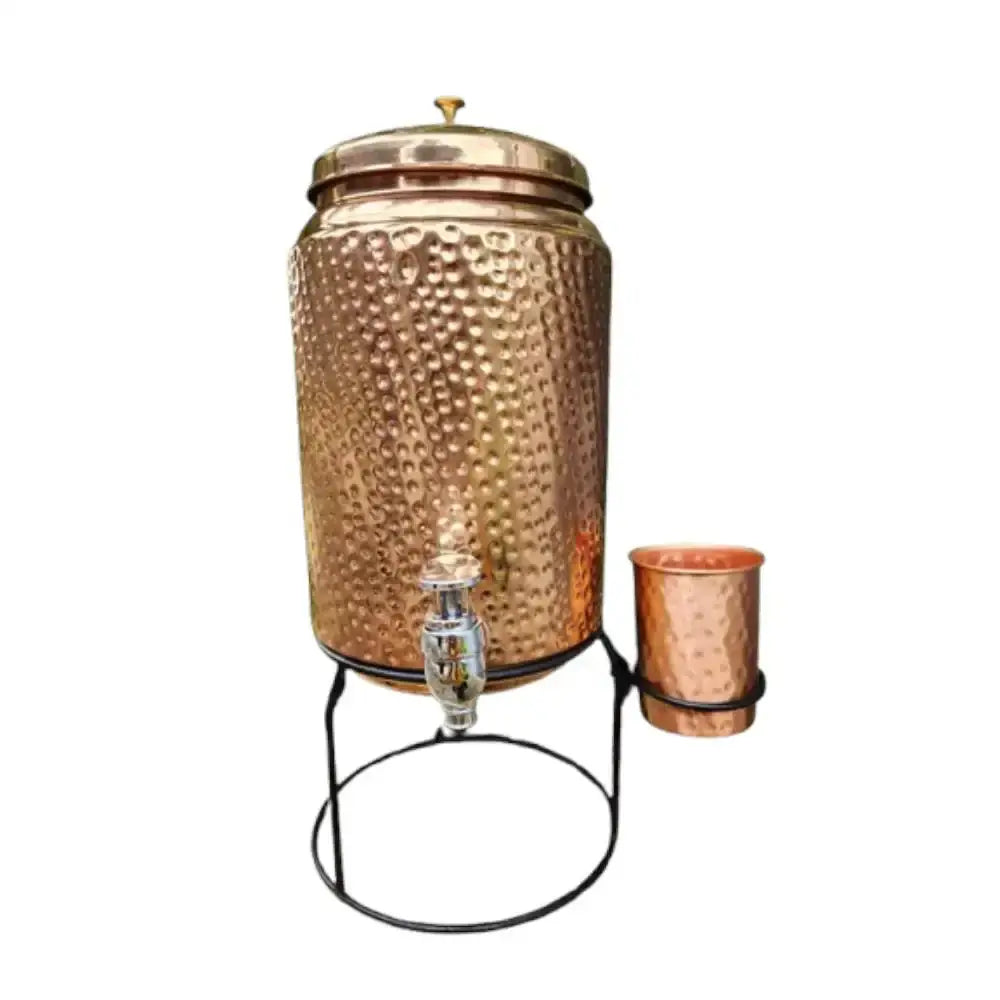 Copper water dispenser with a glass on a white background