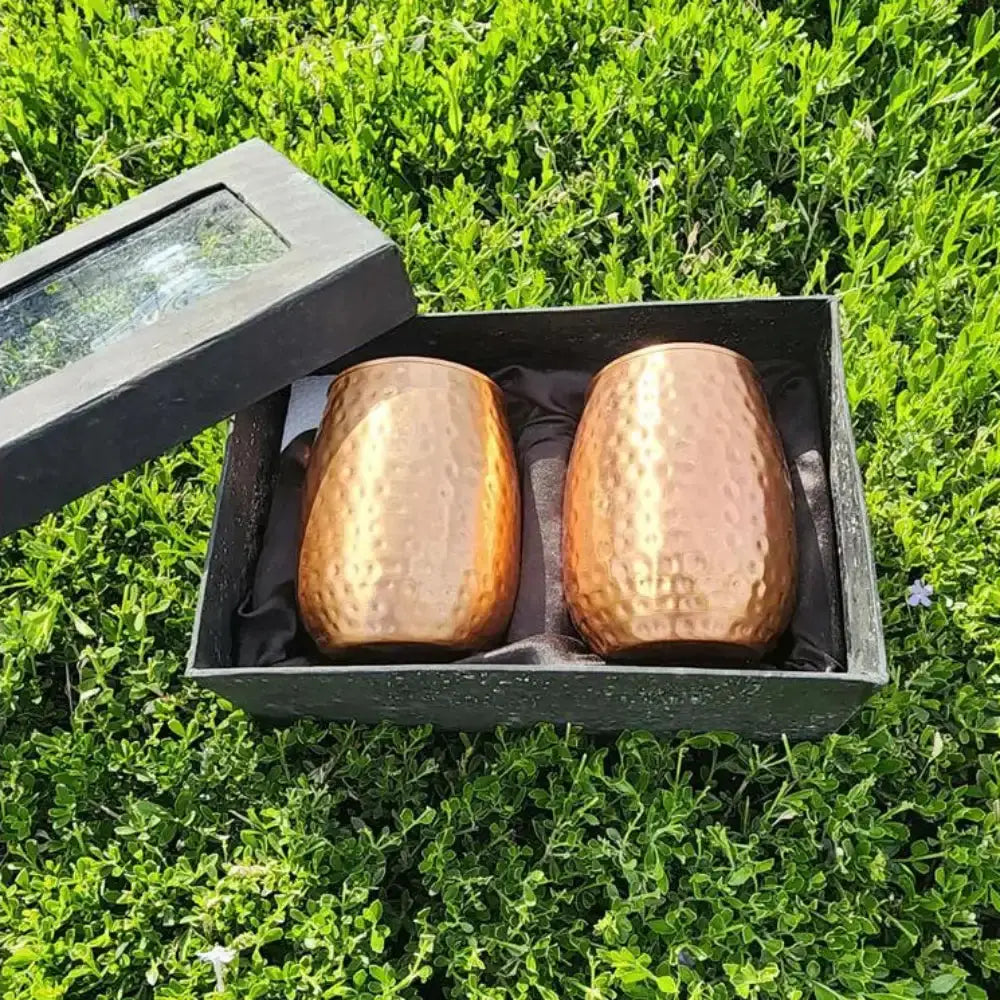 Two copper mugs in a black box on grass