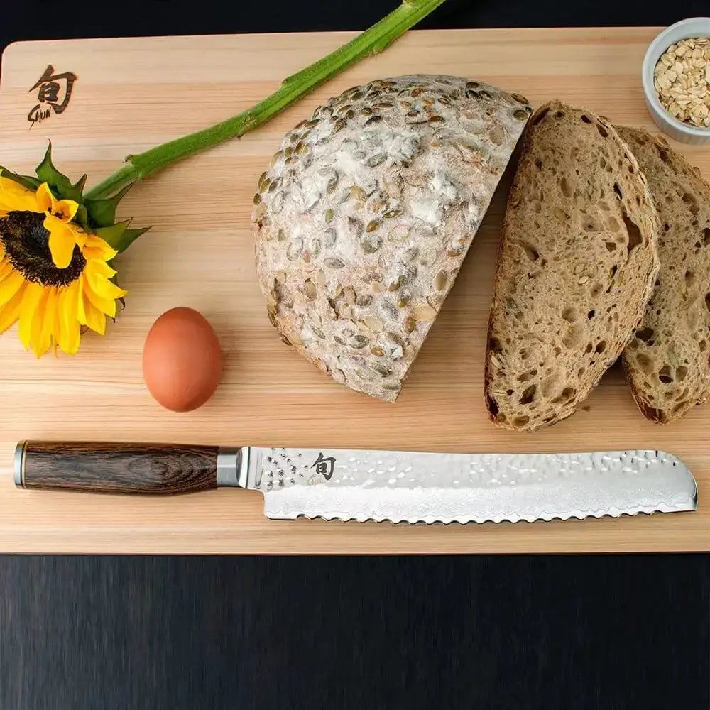Loaf of bread, knife, egg, and sunflower on a wooden cutting board.