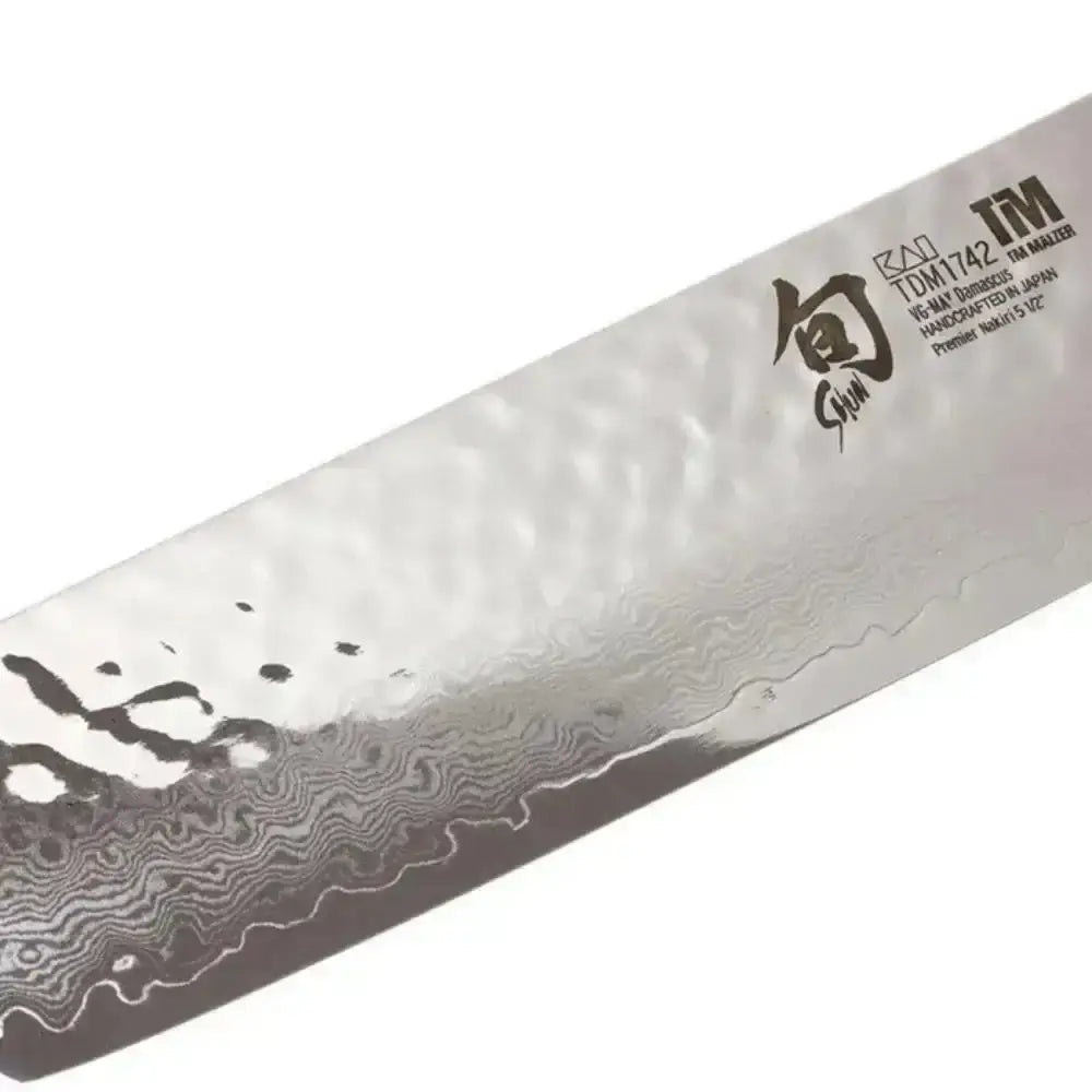 Shun chef's knife blade with Damascus pattern on a white background