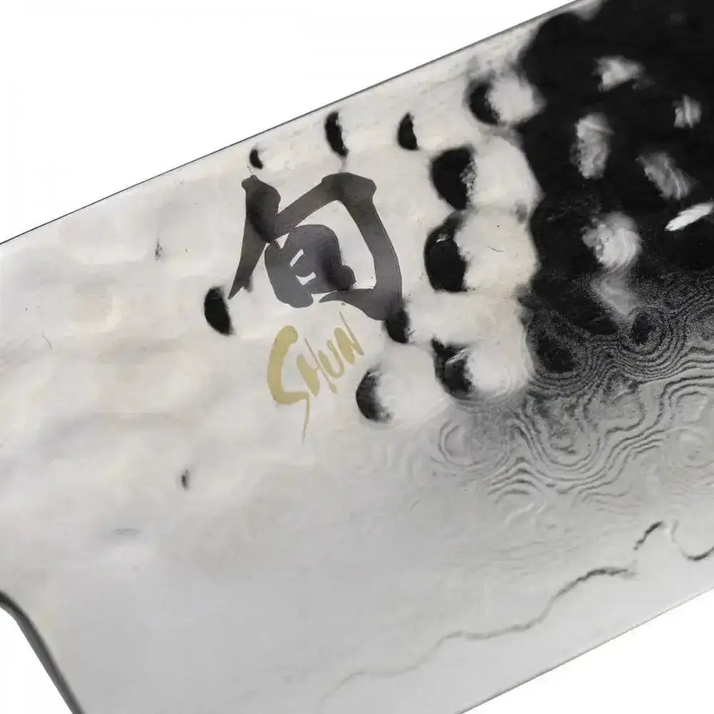 Close-up of a Shun knife blade with engraved logo on a white background
